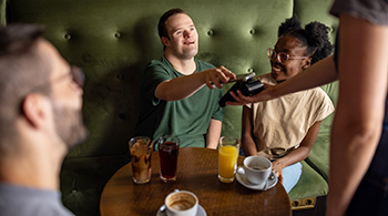 Young man paying for drinks in a pub